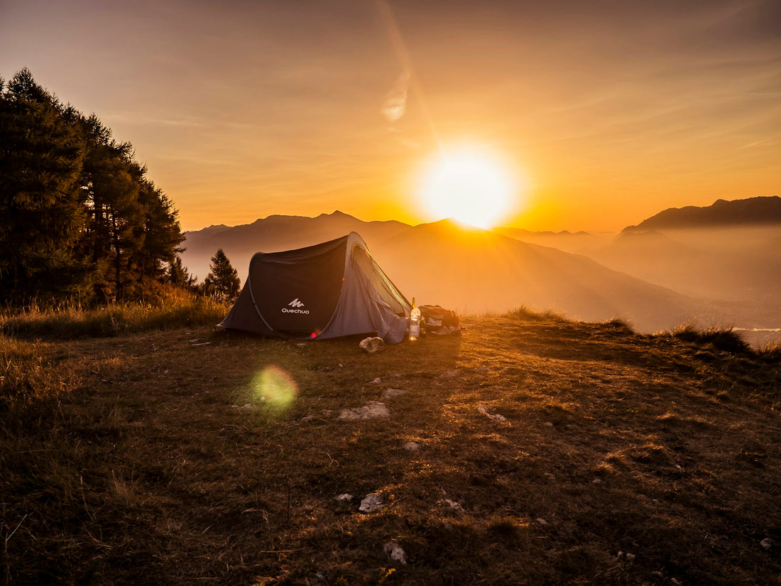 Tienda de campaña tipo iglú en la cima de una montaña al atardecer