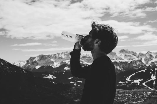 Senderista bebiendo agua de una botella en la cima de una montaña