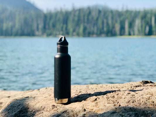 Botella de agua junto a un curso de agua natural