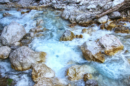 Río rocoso de montaña con agua corriendo entre piedras grises